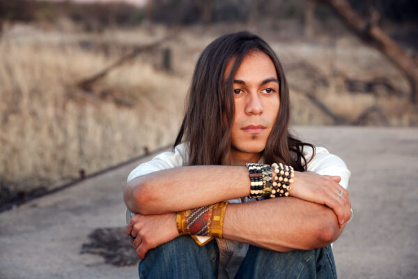 image of man with native american style bracelets looking off in to the distance