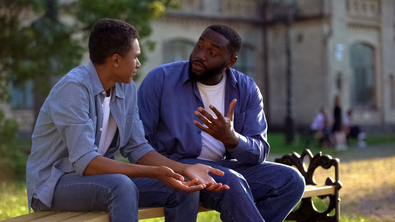 image of two men talking sitting on park bench